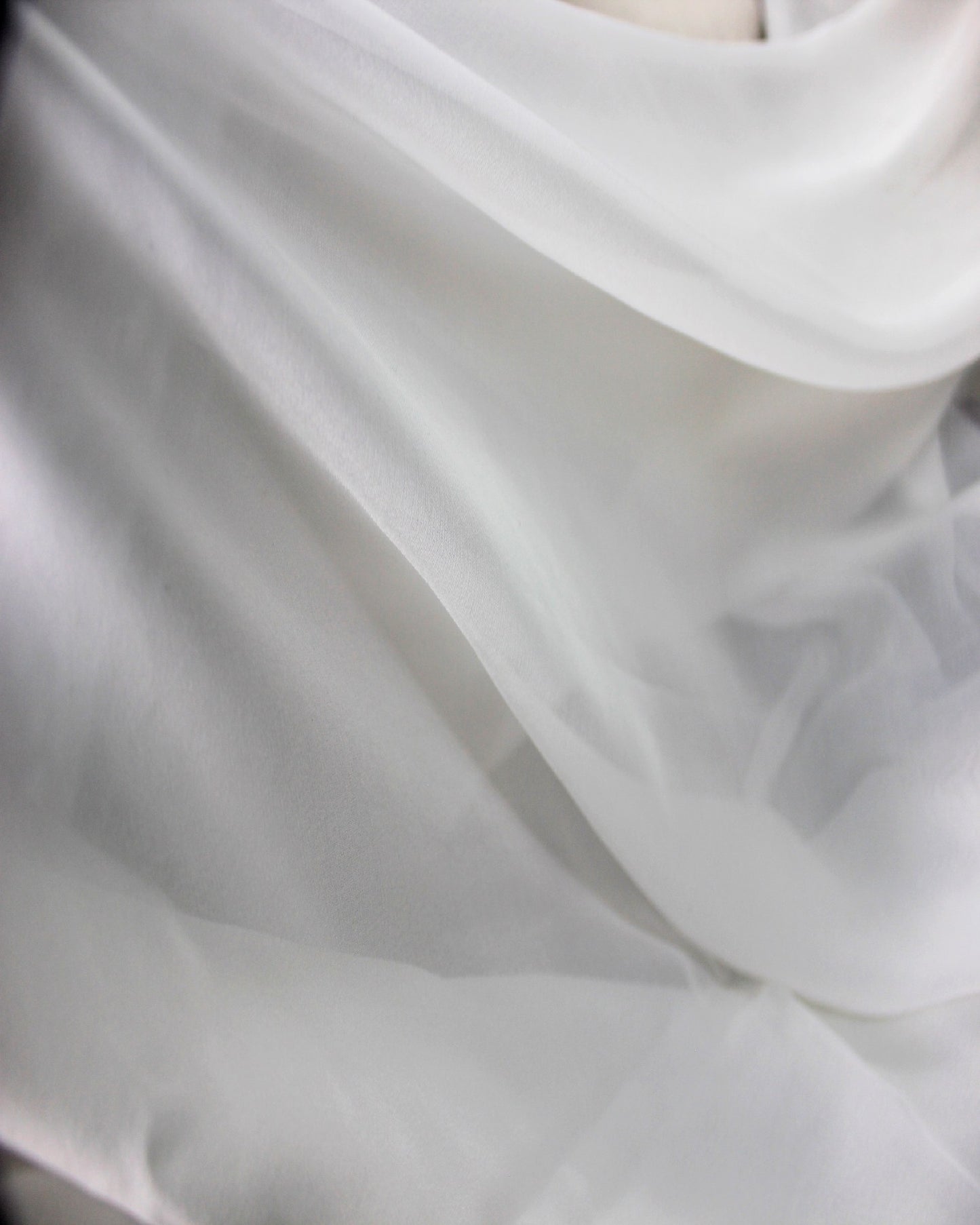 White 10 momme mulberry silk chiffon arranged in broad flowing folds, showing its lightweight movement and airy fluid drape.