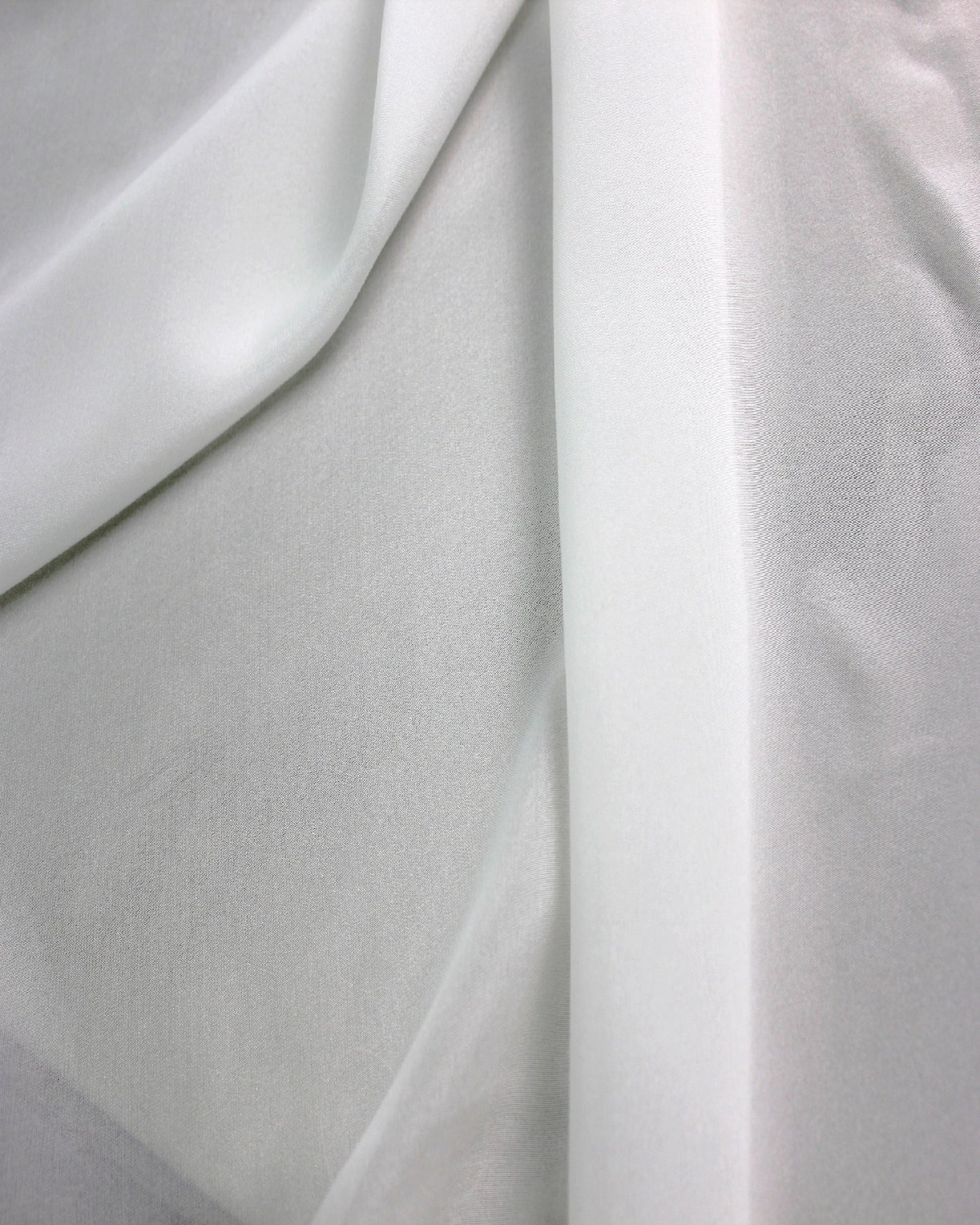 Layered white 10 momme silk chiffon showing translucent overlap, fine woven texture and lightweight sheer construction.