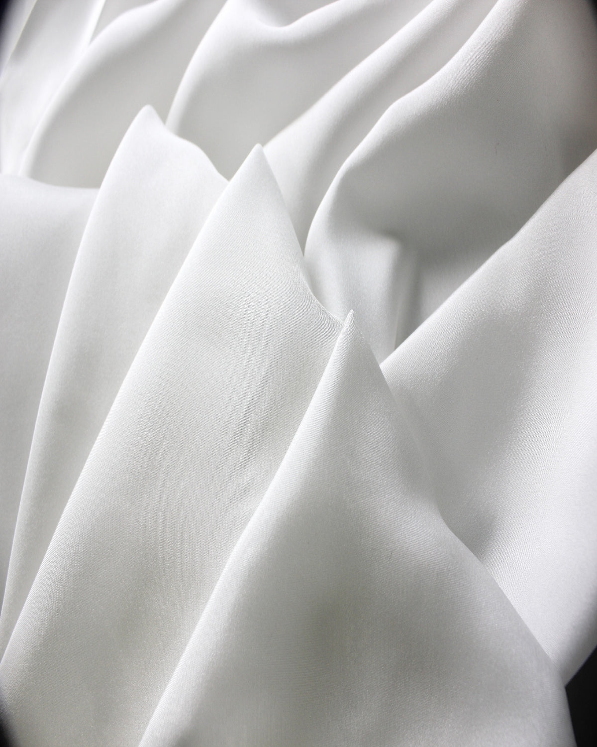 White 12 momme silk Habotai formed into sculpted folds, showing its smooth surface and softly structured lightweight body.