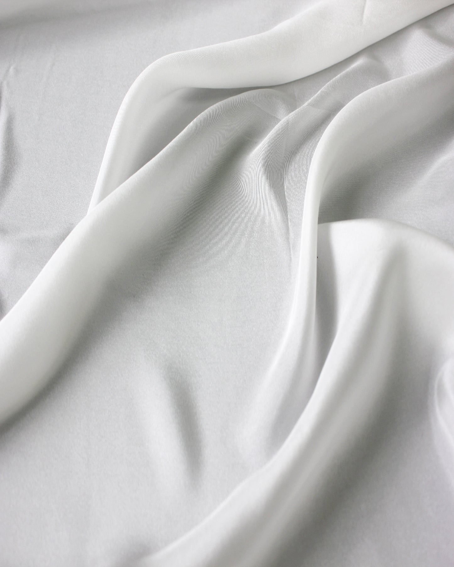 White 12 momme silk Habotai arranged in broad flowing folds, highlighting its lightweight body and graceful drape.