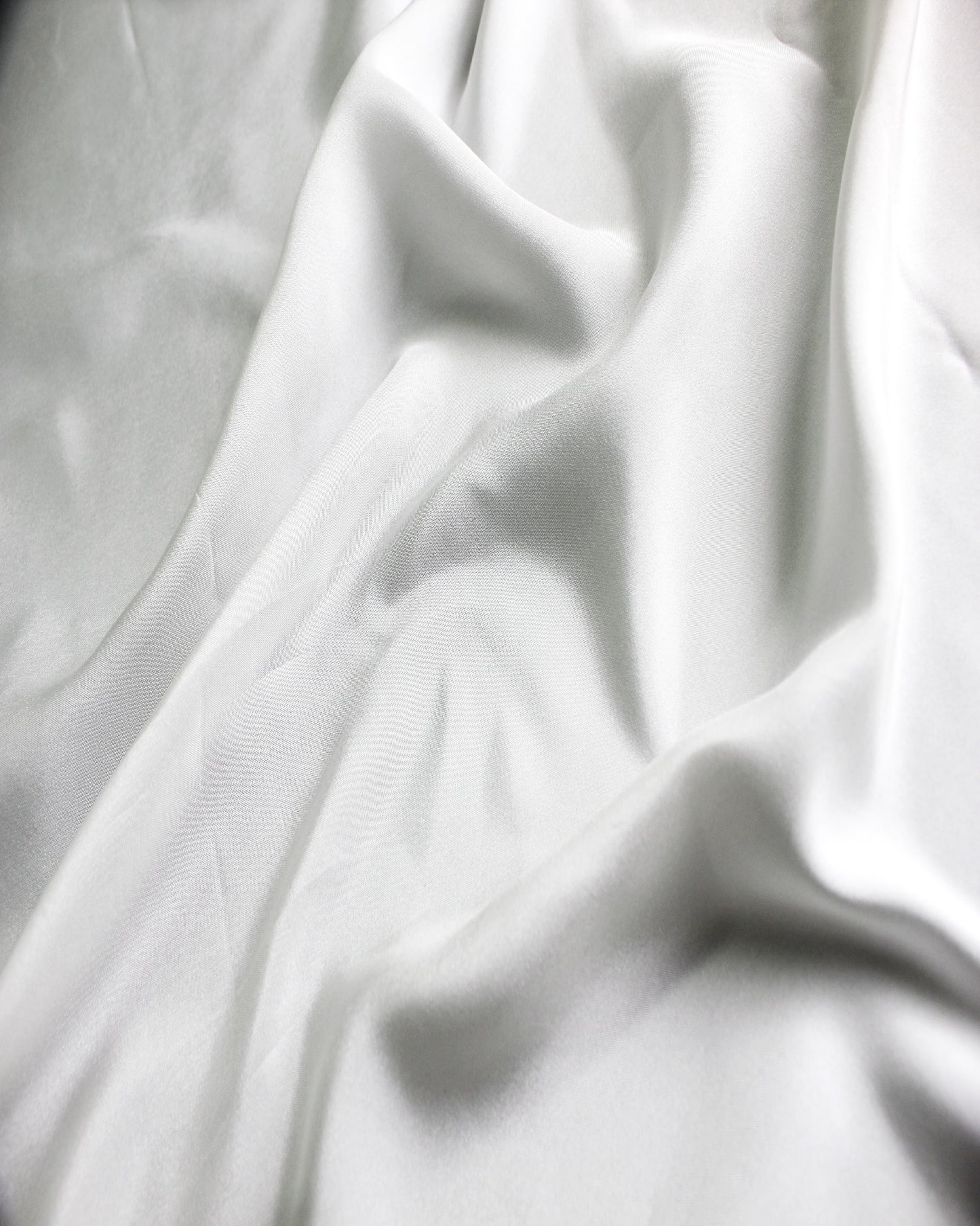 White 12 momme silk Habotai gathered into soft folds, showing its supple character and subtle silk sheen.