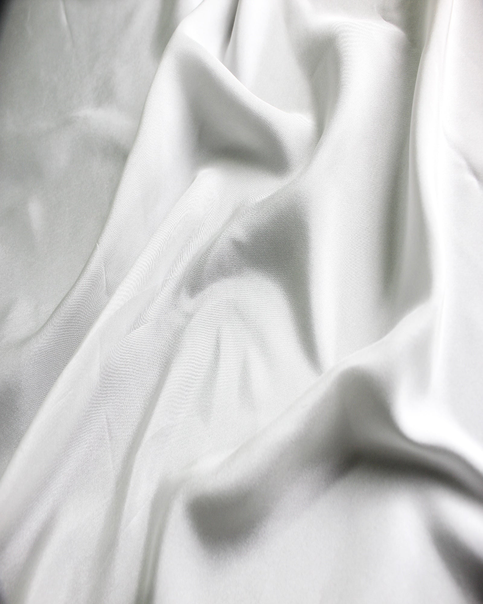 White 12 momme silk Habotai gathered into soft folds, showing its supple character and subtle silk sheen.