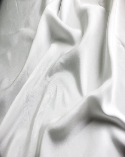 White 12 momme silk Habotai gathered into soft folds, showing its supple character and subtle silk sheen.