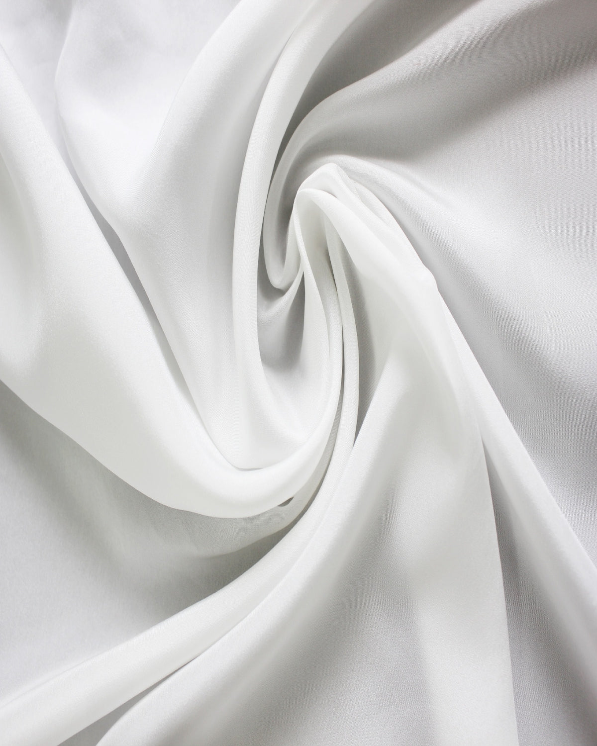 White 12 momme silk Habotai fabric arranged in flowing folds, showing its smooth surface, soft sheen and fluid drape.