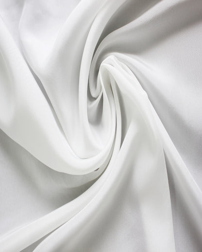 White 12 momme silk Habotai fabric arranged in flowing folds, showing its smooth surface, soft sheen and fluid drape.