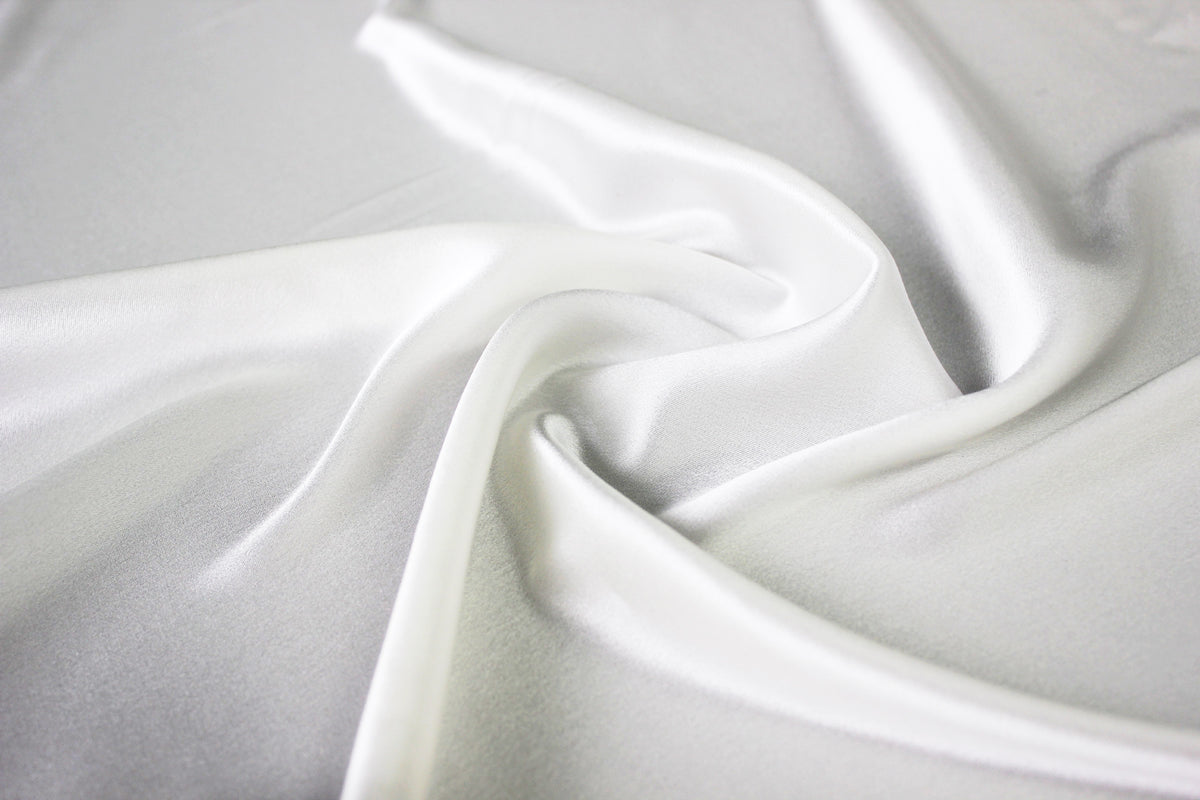 MingSilk 19 momme mulberry silk charmeuse in bleached white with fluid folds and soft satin lustre.
