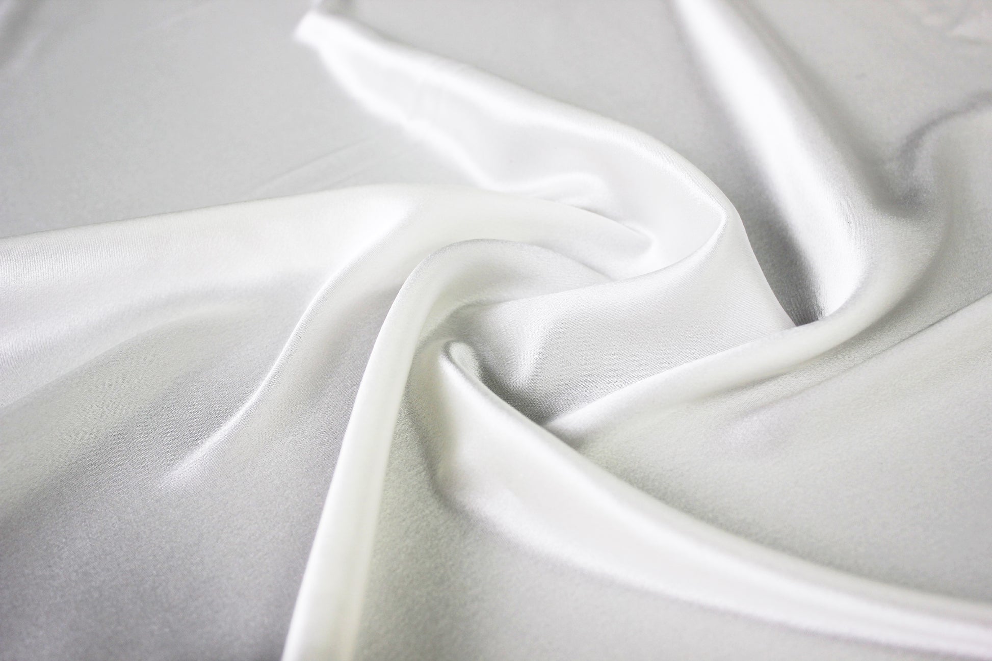 MingSilk 19 momme mulberry silk charmeuse in bleached white with fluid folds and soft satin lustre.