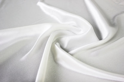 MingSilk 19 momme mulberry silk charmeuse in bleached white with fluid folds and soft satin lustre.