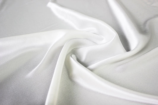 MingSilk 19 momme mulberry silk charmeuse in bleached white with fluid folds and soft satin lustre.