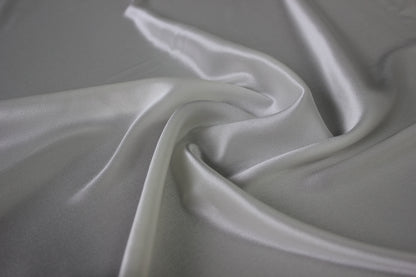 MingSilk 19 momme mulberry silk charmeuse in bleached white with fluid folds and soft satin lustre.