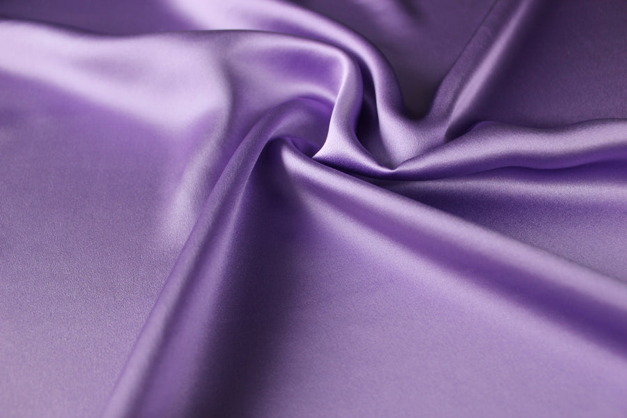 Lavender purple 19 momme mulberry silk charmeuse fabric with fluid folds and a smooth satin lustre.