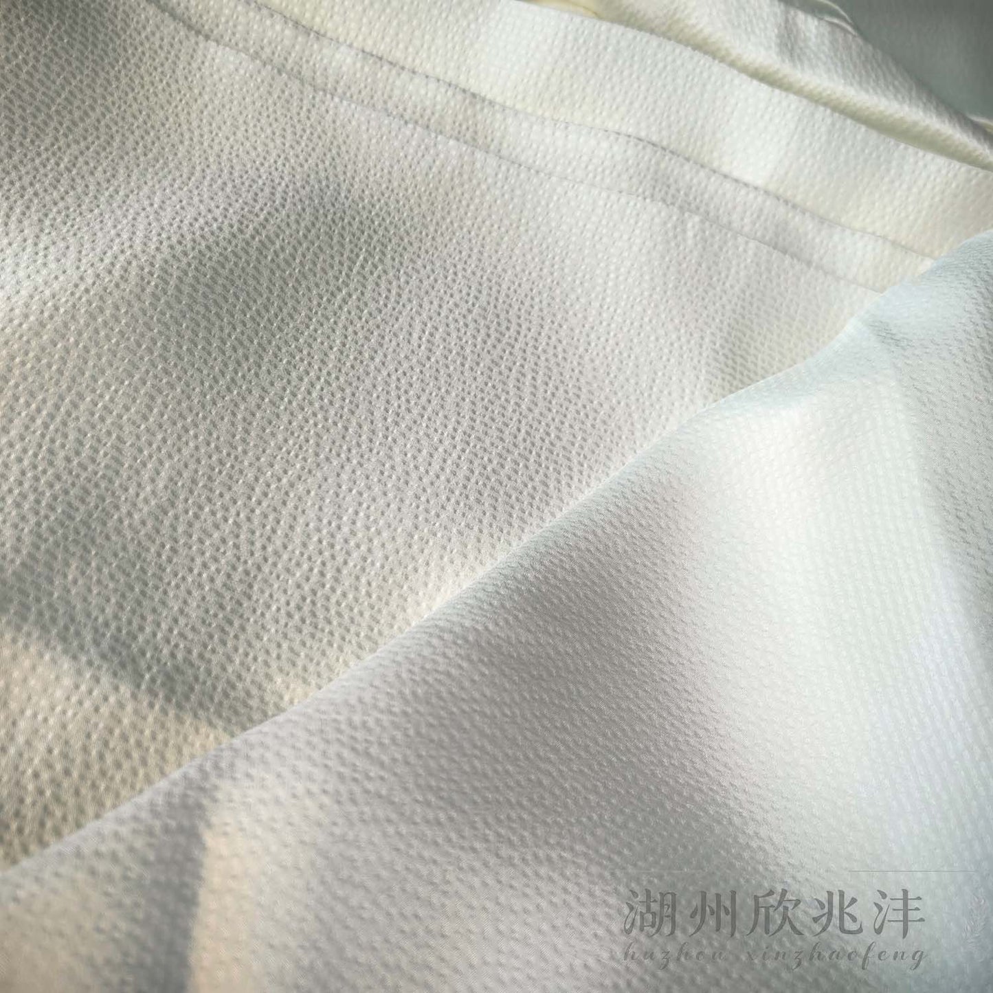 Backlit 19 momme silk pearl satin showing its woven structure, subtle translucency and fine surface texture.
