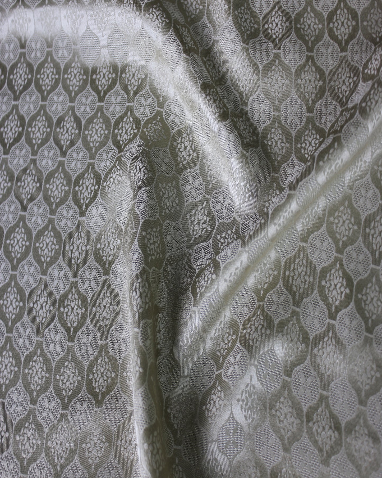 19 momme Sangbo jacquard satin fabric showing soft silk lustre across raised folds and woven motifs