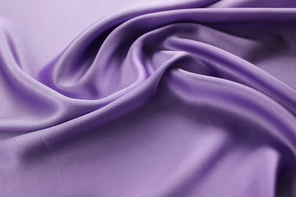 19 momme mulberry silk charmeuse fabric in lavender purple, showing fluid drape and soft satin highlights.