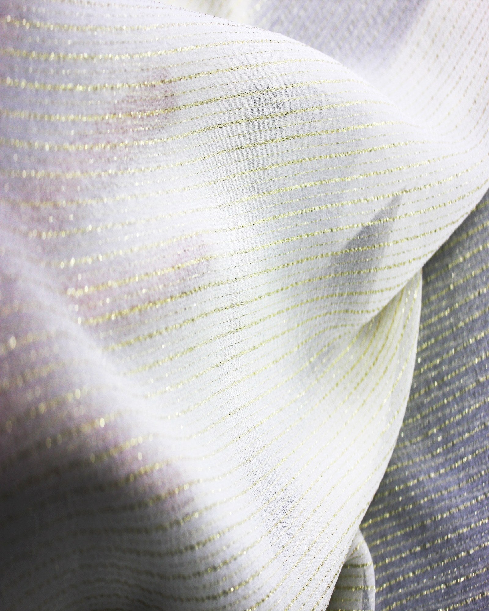 Detail of white silk Yoryu fabric showing reflective gold metallic stripe yarns under directional light.