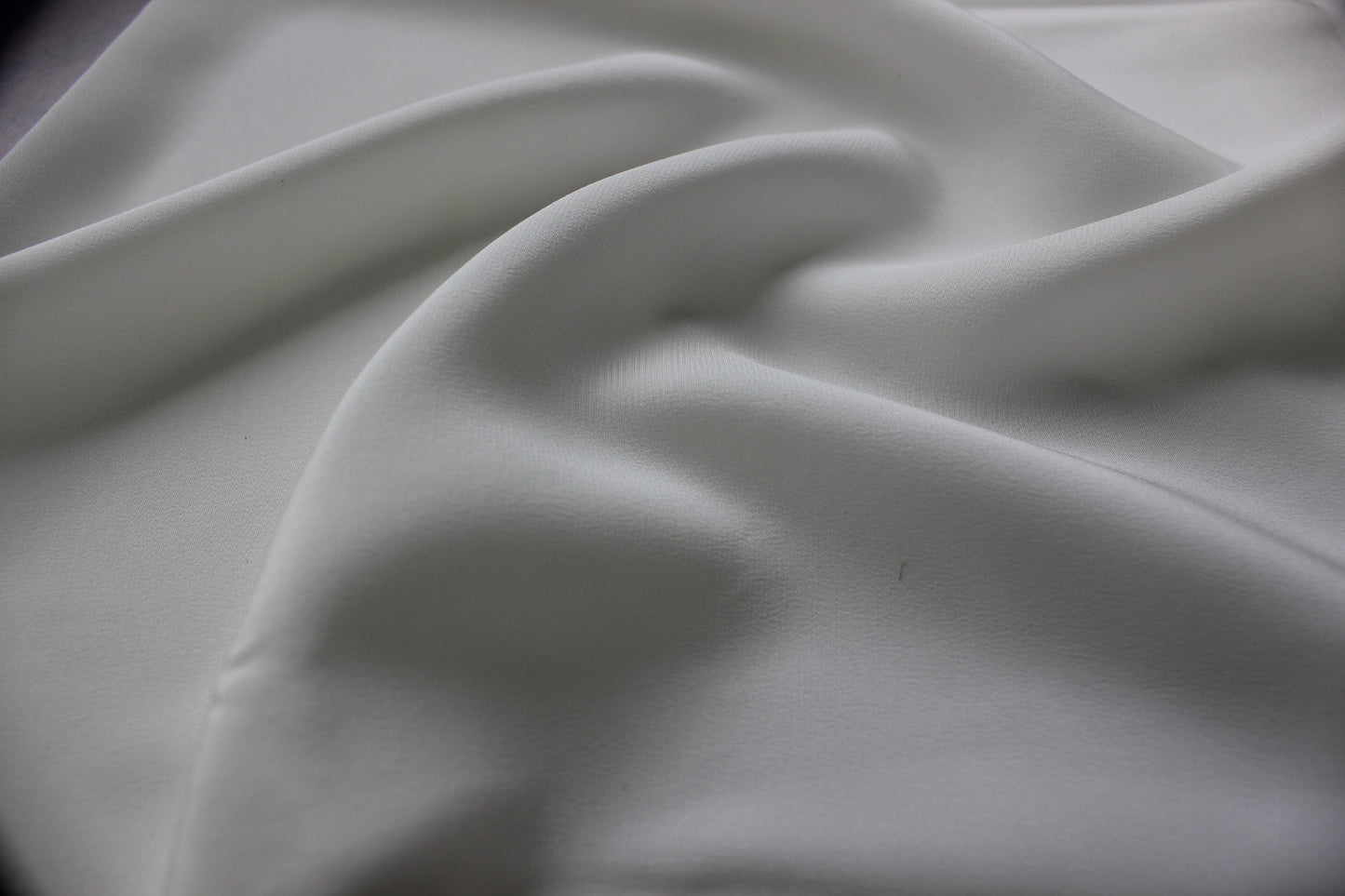 Close view of bleached white MingSilk silk charmeuse showing a smooth fine surface and soft drape.