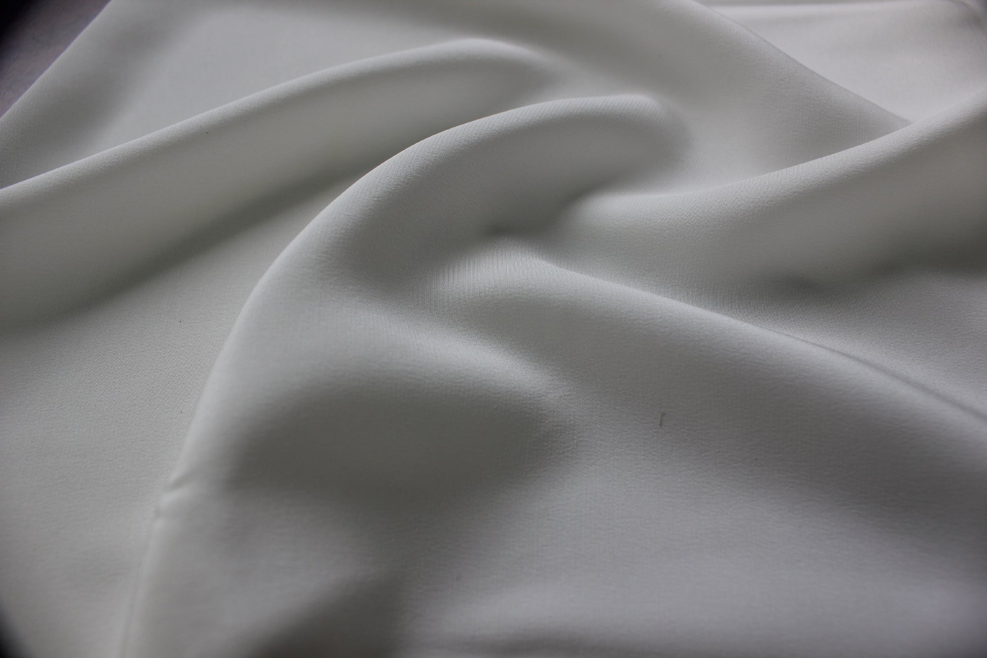 Close view of bleached white MingSilk silk charmeuse showing a smooth fine surface and soft drape.