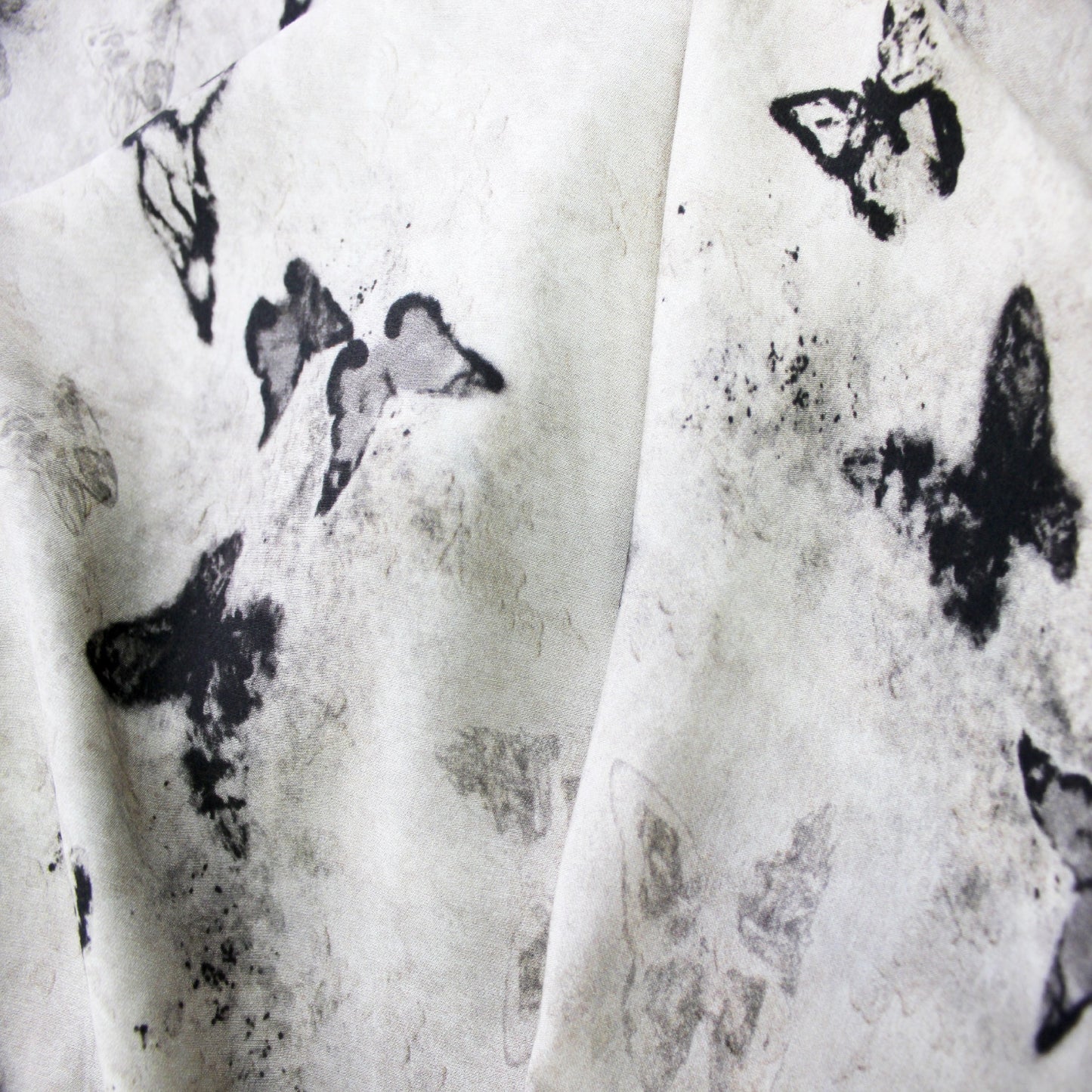 Macro close-up view of ink wash butterfly print and fine texture on silk rayon fabric