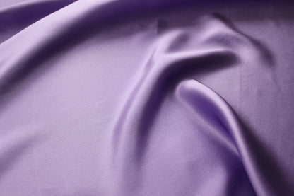 Close-up of lavender silk charmeuse showing a smooth satin face, fine surface texture and pearlescent lustre.