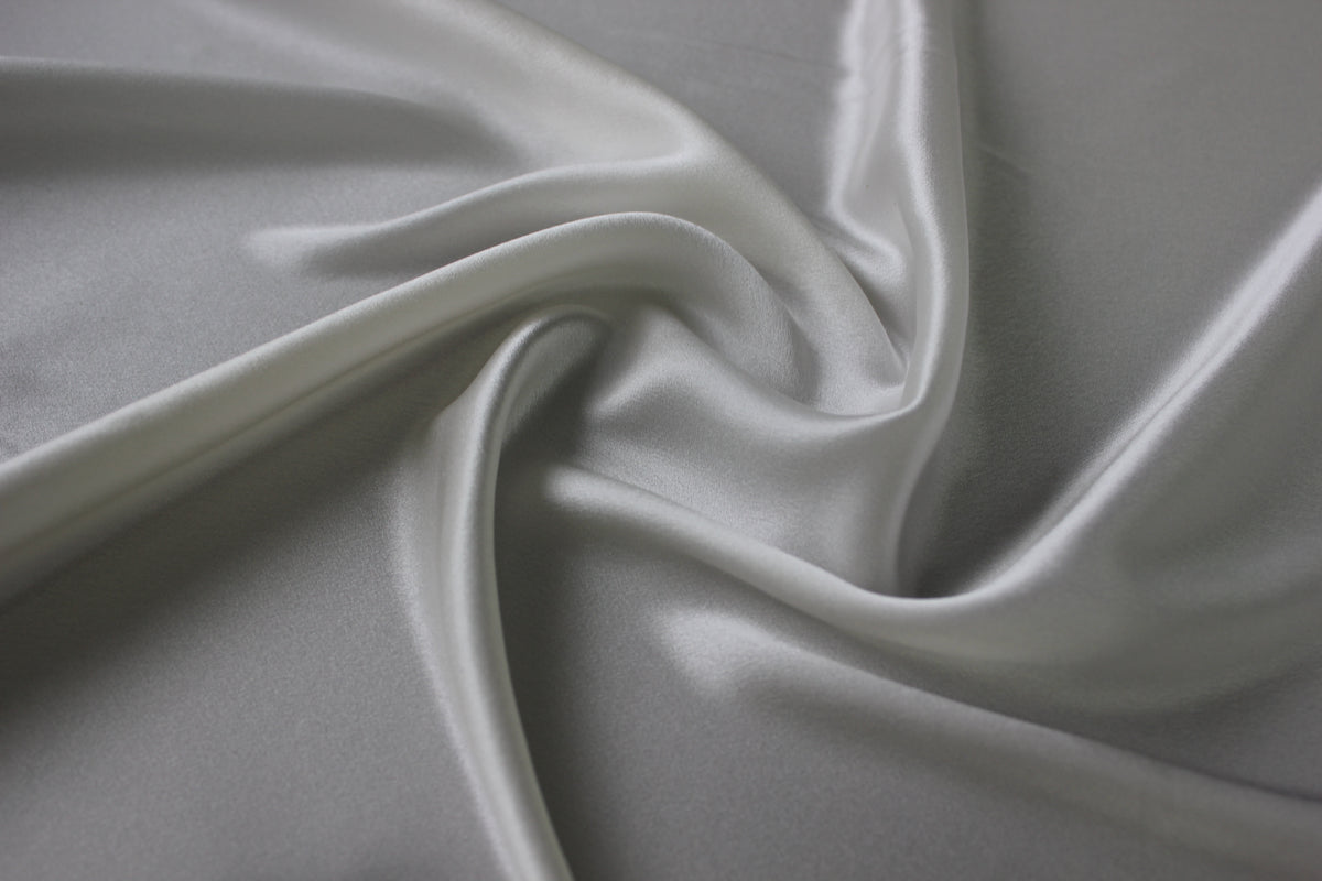 Close-up of MingSilk silk charmeuse showing its smooth satin sheen, pearly highlights and flowing folds.