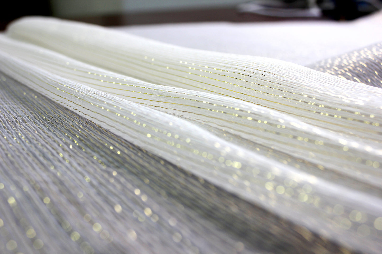 Gold-tone metallic yarns catching light across sheer MingSilk silk Yoryu fabric.