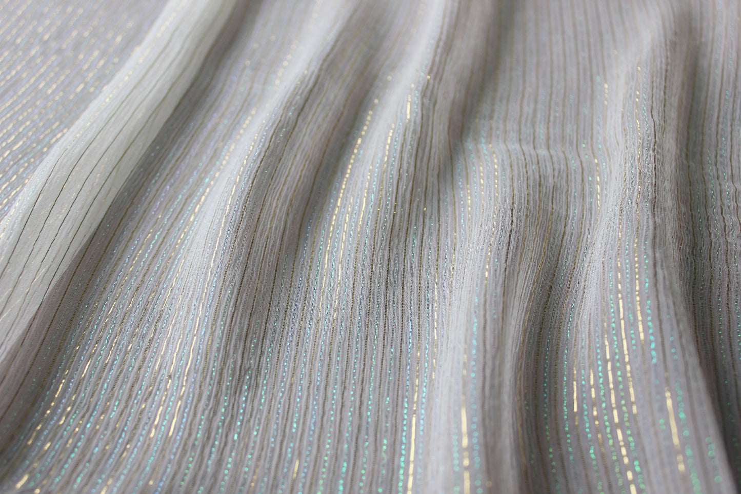 Iridescent gold, aqua and blue-green metallic stripes catching light across MingSilk Yoryu silk.